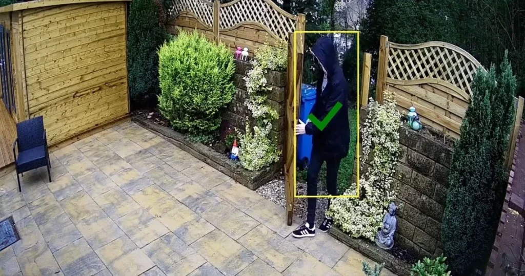 Camera view with a detection box around a person in a courtyard