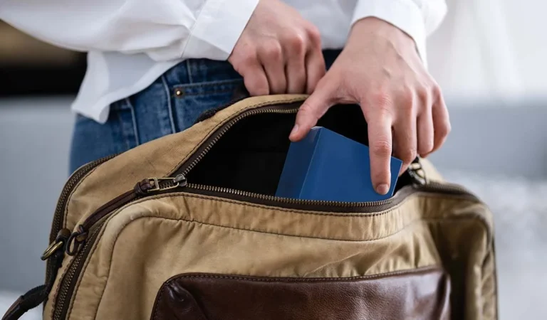 Person placing a small blue box into an open bag