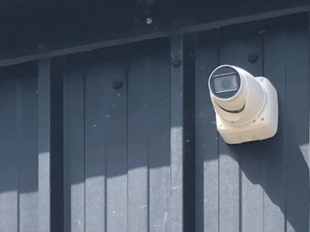 White security camera mounted on a dark exterior wall
